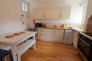 a kitchen with white cabinets and a wooden floor at End Cottage, Bakewell in Bakewell