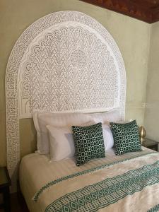 a bed with a white headboard with three pillows at Riad Amalia in Marrakech