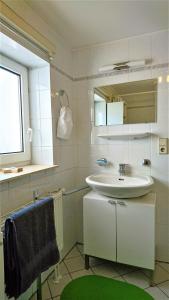 ein weißes Badezimmer mit einem Waschbecken und einem Spiegel in der Unterkunft Citywohnung im Paulusviertel II in Halle an der Saale