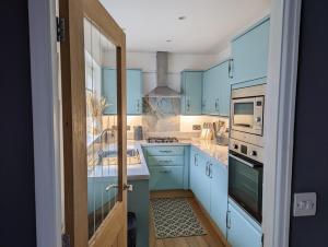 eine blaue Küche mit blauen Schränken und einem Herd Top-Backofen in der Unterkunft Swan Cottage in Barnard Castle