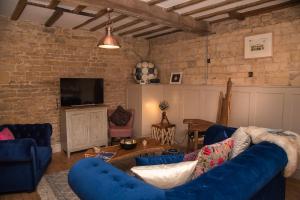 uma sala de estar com um sofá azul e uma televisão em No.4 The Old Coach House em Blockley