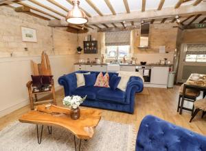 uma sala de estar com um sofá azul e uma mesa em No.4 The Old Coach House em Blockley