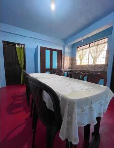 una sala da pranzo con tavolo e sedie bianchi di GREEN HILLS a Cherrapunji