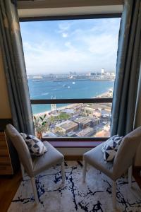 Pokój z 2 krzesłami i dużym oknem w obiekcie Nirvana Home w Dubaju
