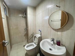 La salle de bains est pourvue de toilettes, d'un lavabo et d'un miroir. dans l'établissement Modern Condo near US Embassy and St Lukes Ermita, à Manille
