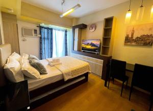 a bedroom with a bed and a tv on the wall at Condo near US Embassy and St Lukes Ermita in Manila