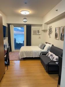 a bedroom with a bed and a couch and a window at Modern Condo near US Embassy and St Lukes Ermita in Manila
