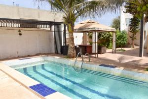 a swimming pool with a palm tree and a gazebo at Le petit coccon de LUZ in Mbour