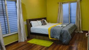 1 dormitorio con 1 cama con paredes y ventanas de color amarillo en Samrudhi Villa Home, en Hampi