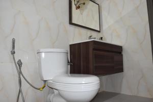 a bathroom with a white toilet and a sink at Le petit coccon de LUZ in Mbour