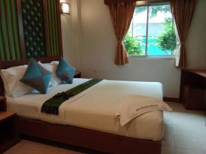 a bedroom with a large bed with a window at เดอะกรีนฟอเรสท์ รีสอร์ท in Hat Yai