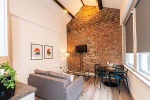 a living room with a couch and a brick wall at One Bedroom Apartments in Liverpool City Centre in Liverpool