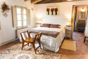 1 dormitorio con 1 cama y 1 silla en Mas Gran de Cruïlles - Mas Rural - Hotel & Events en Cruïlles