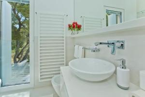 a white bathroom with a sink and a window at Villa Madeleine Hvar in Hvar