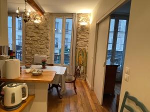 a kitchen and dining room with a table and some windows at One-Bedroom Apartment by the Eiffel Tower: your home in the heart of Paris in Paris