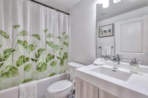 a bathroom with a toilet and a shower curtain with plants at RivetStays - The Jarvis in Toronto