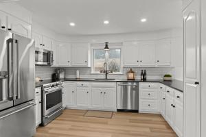 a kitchen with white cabinets and stainless steel appliances at Stay On The Cape Vacation Rentals: Immaculate Home 2 Acres Short Walk To Beach in Bourne
