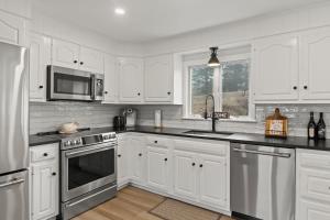 a kitchen with white cabinets and stainless steel appliances at Stay On The Cape Vacation Rentals: Immaculate Home 2 Acres Short Walk To Beach in Bourne +56 photos