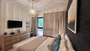 a bedroom with a bed and a television and a chandelier at Apartamento Punta Cana w/Pool & Beach in Punta Cana