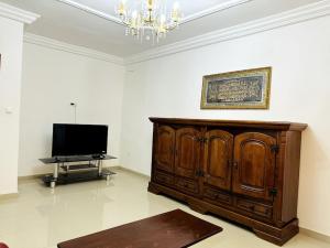 ein Wohnzimmer mit einem TV und einem Holzschrank in der Unterkunft Maison fonctionnelle idéalement située à Dakar in Dakar