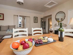 a table with a bowl of fruit and a bottle of wine at Summerhow Retreat in Kendal