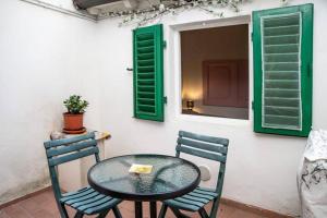 a table with two chairs and a window with green shutters at In the small heart of Florence + Corte privata+ WiFi+AC in Florence