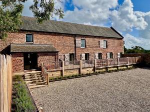 a brick building with a wooden fence in front of it at The Barn at Plas Ashpool Sleeps 8 in Llandyrnog