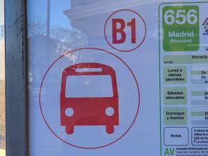 ein Schild für eine Bushaltestelle mit rotem Bus in der Unterkunft SUKI HOUSE Chalet 1 in Madrid