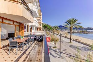 a patio with a table and chairs next to a beach at Emma Beachfront Apartment in Port de Pollensa