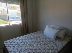 a bedroom with a bed with a pillow and a window at Apartamentos Beira Mar in Laranjal