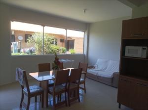 a living room with a table and chairs and a bed at Apartamentos Beira Mar in Laranjal