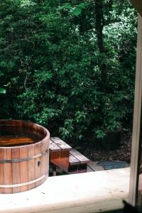 a wooden barrel with a picnic table in front of a tree at The Forest Bathhouse - Sauna, Soak, & Luxury in Fairview +12 photos