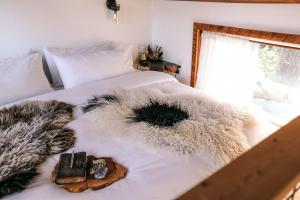 a bedroom with a bed with a furry blanket and a window at The Forest Bathhouse - Sauna, Soak, & Luxury in Fairview
