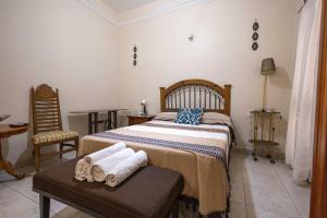 Hotel Patio Pombo في مدينة أواكساكا: غرفة نوم بسرير وطاولة مع مناشف