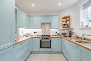 a kitchen with blue cabinets and a sink at Yew Tree Cottage in Margate