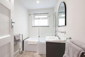 a bathroom with a sink and a tub and a mirror at Yew Tree Cottage in Margate