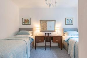 a bedroom with two beds and a desk with a mirror at Yew Tree Cottage in Margate