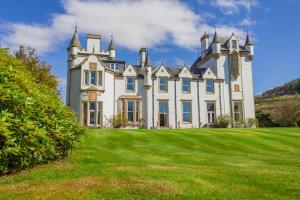 uma grande casa branca com um grande campo de relva em Cairngorms Castle em Cray