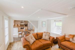 a living room with two brown couches and a kitchen at Cairngorms Cottage in Cray