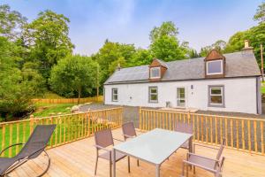 eine Terrasse mit einem Tisch und Stühlen sowie ein Haus in der Unterkunft Cairngorms Cottage in Cray