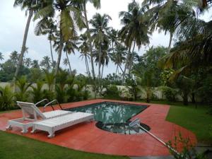 ein Pool mit einer Bank und einem Stuhl daneben in der Unterkunft Fool's Paradise in Alappuzha