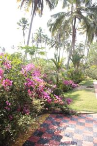 um jardim com flores cor-de-rosa e palmeiras em Fool's Paradise em Alappuzha