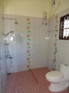 a bathroom with a white toilet and a shower at Fool's Paradise in Alleppey