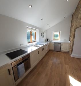 uma grande cozinha com armários brancos e pisos de madeira em Kinley Tower 