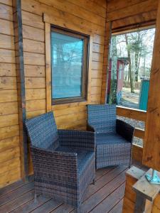 two wicker chairs on the porch of a cabin at 38 m Sommer-Blockhäuschen im Spreewald in Heideblick