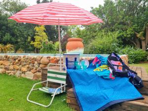 einen Picknicktisch mit einem Sonnenschirm und einem Stuhl in der Unterkunft Angel 8 AirBnB Family Apartment in Robertson