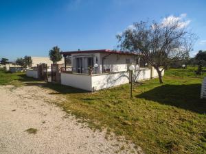 a small white house with a fence in a field at Risa Apulia in Torre Lapillo