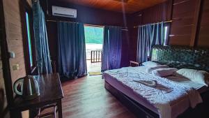 1 dormitorio con cama, mesa y ventana en The Jeti Mangrove - Ecolodge, Cottage, Restaurant & Kali Biru, Blue River en Rabia