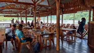 un grupo de personas sentadas en mesas en un restaurante en The Jeti Mangrove - Ecolodge, Cottage, Restaurant & Kali Biru, Blue River, en Rabia