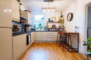 a kitchen with white cabinets and a wooden floor at Comfy 1-Bed Apartment in London in London